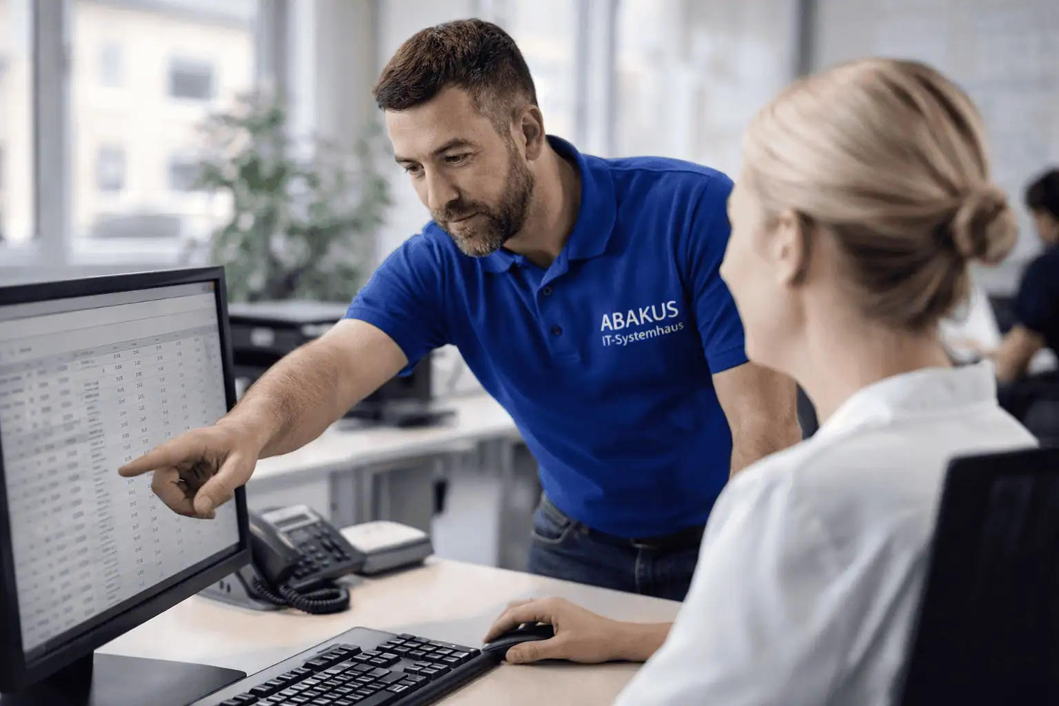 ABAKUS IT-Techniker erklärt einer Kundin eine Tabelle am PC im Buero